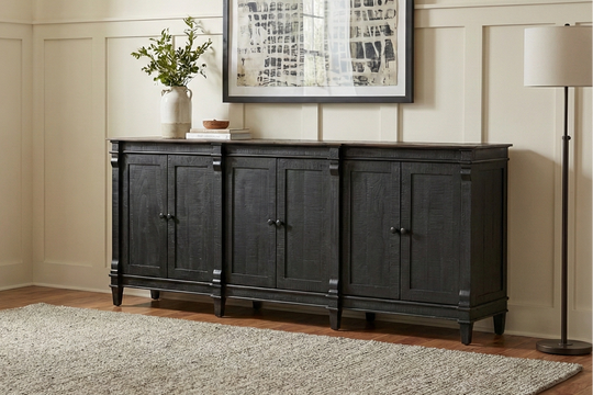 Black sideboard in a room with a window, plants, and a lamp.