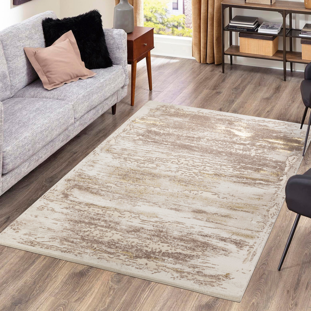 Living room with a gray sofa, patterned rug, and wooden floor.