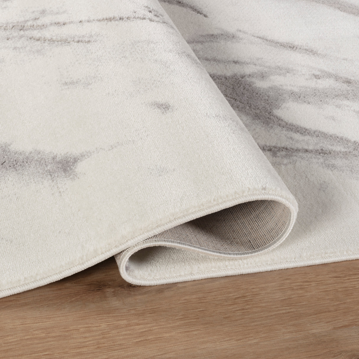 Close-up of a textured rug with a subtle pattern on a wooden floor.