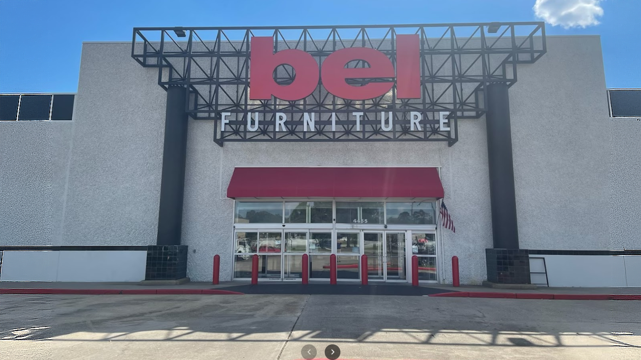 Bel Furniture store front with red and black branding against a blue sky.