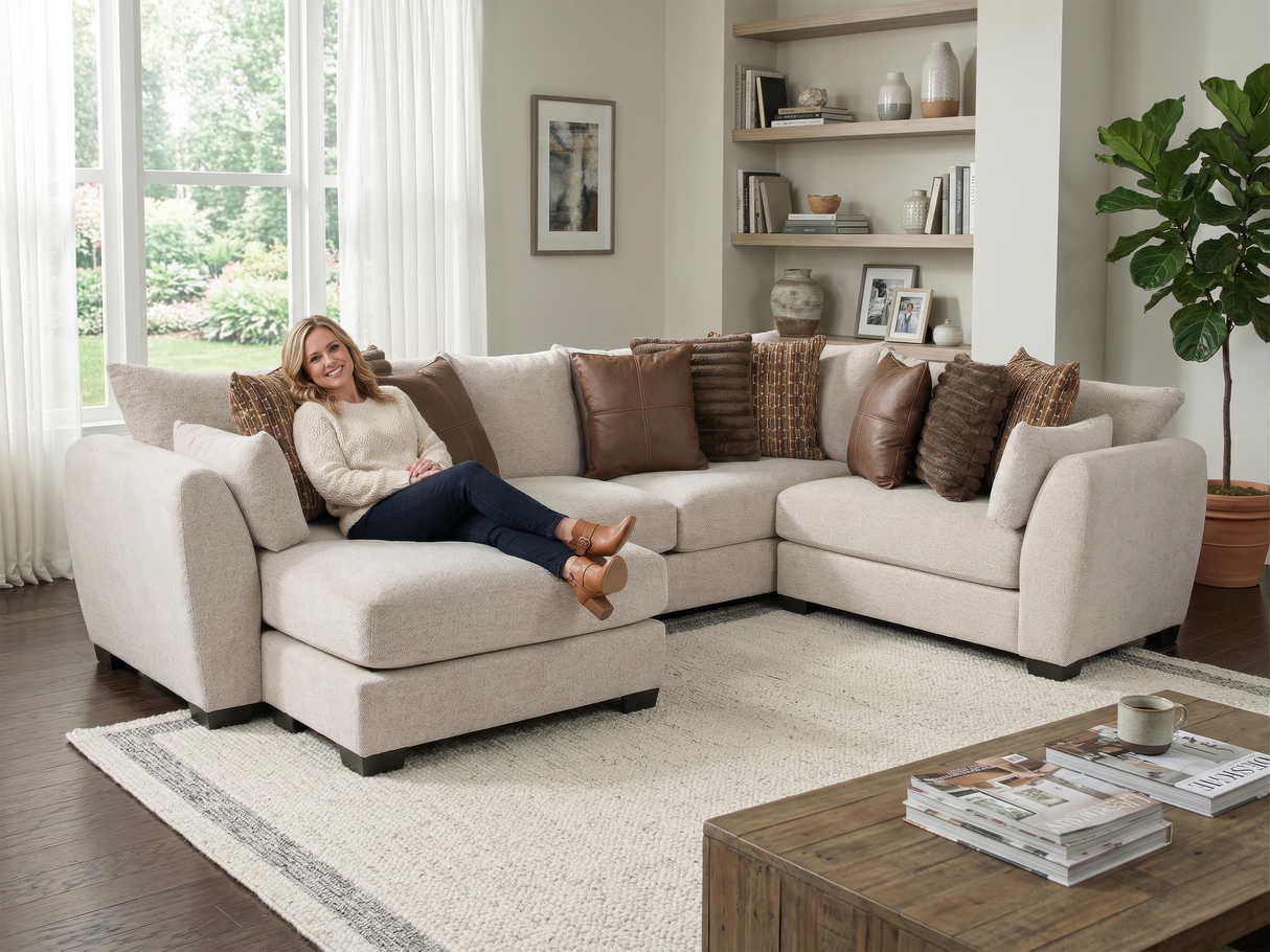 Woman sitting on a beige sectional sofa in a living room with a coffee table and decor.