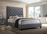 Gray upholstered bed in a modern bedroom with large windows.