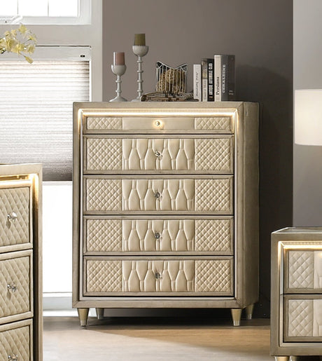 A luxury bedroom furniture set featuring a tufted cream upholstered bed, matching nightstands, a dresser with an in-bed fireplace, a tall chest, and a large mirror, all in a modern gray and beige bedroom setting.