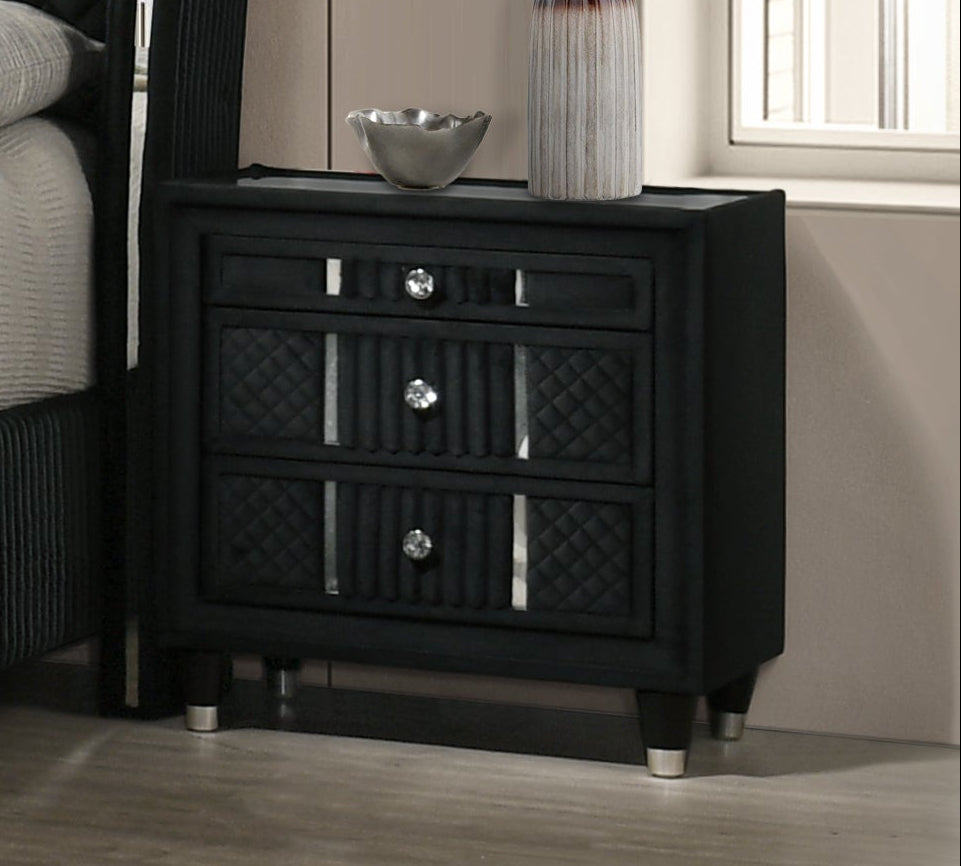 Modern bedroom with black upholstered bed, nightstands, and a fireplace.