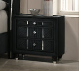 Modern bedroom with black upholstered bed, nightstands, and a fireplace.