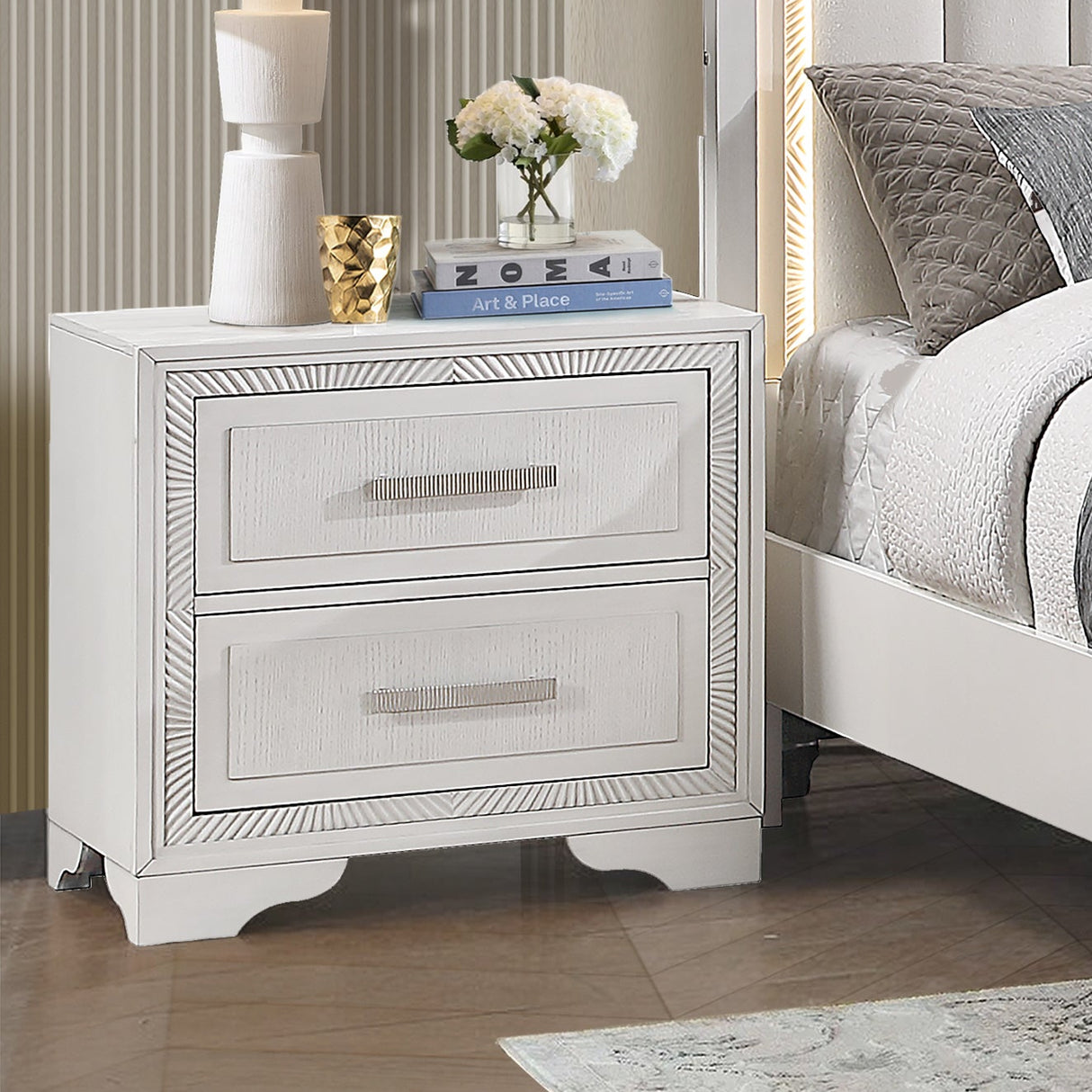 White bedroom set with bed, nightstands, dresser, and mirror in a room with large windows.