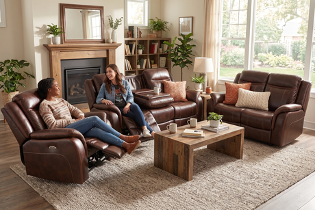 Two women sitting on brown leather recliners in a living room with a coffee table and decor.