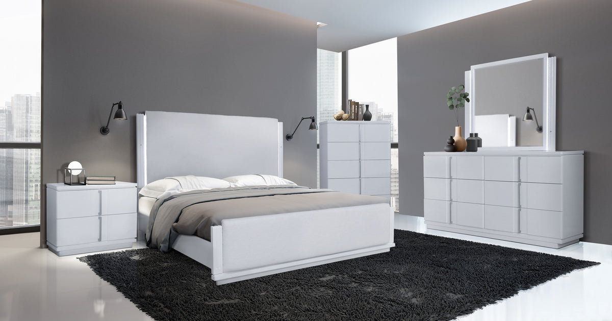 Modern bedroom with white furniture set including bed, dresser, and mirror.