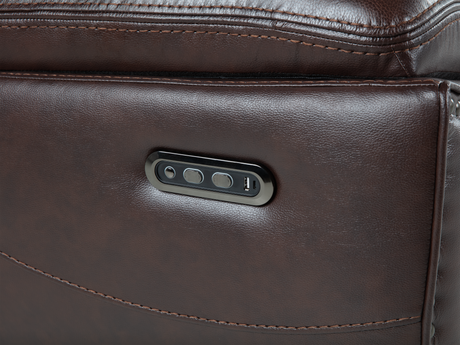 Close-up of a brown leather bag with a metallic label featuring ports.