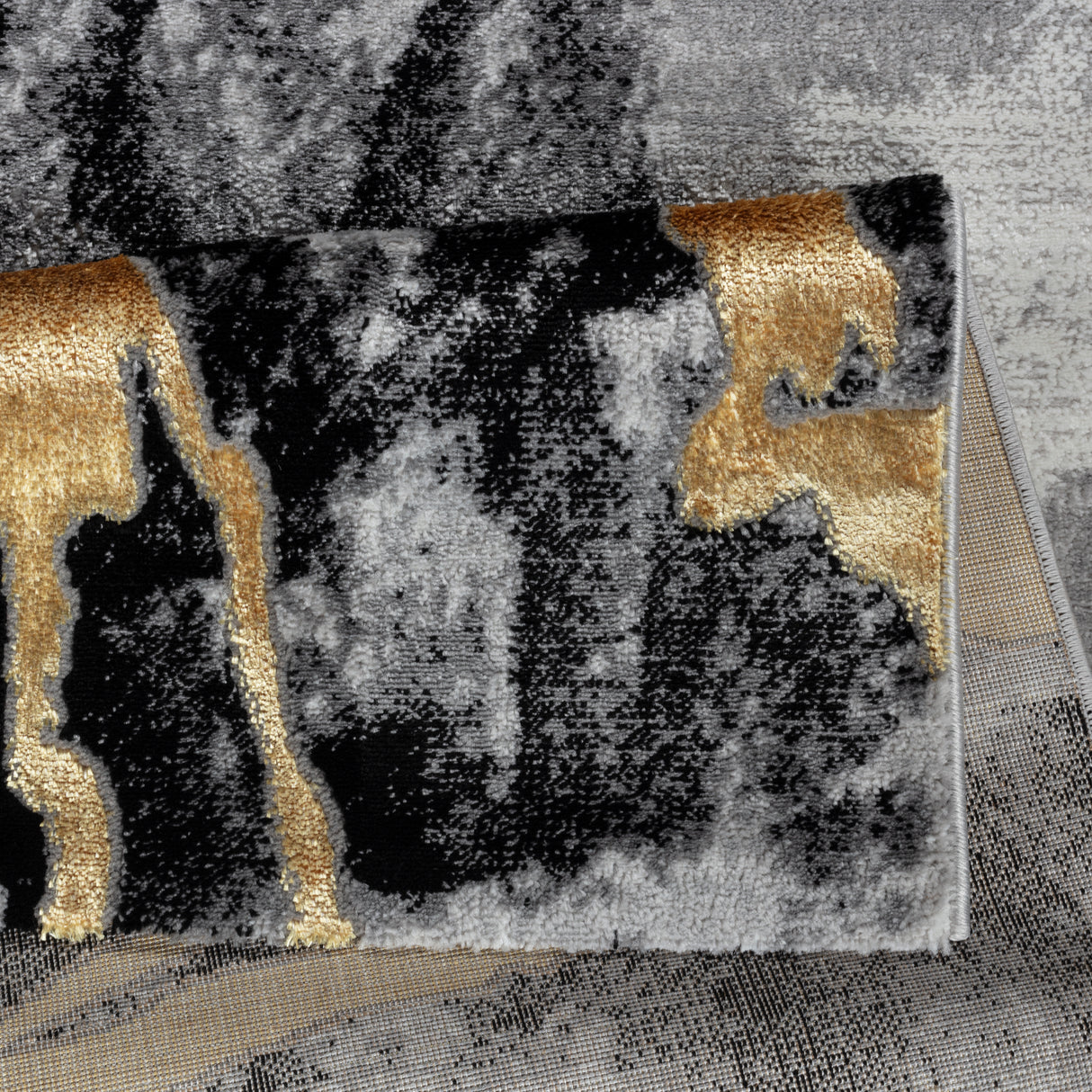 Close-up of a textured rug with black, gold, and gray patterns.