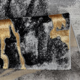 Close-up of a textured rug with black, gold, and gray patterns.