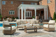 Outdoor patio set with furniture and decor in front of a brick house.
