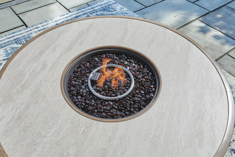 Beige round fire pit table with dark pebbles and flame feature on wooden deck - Bel Furniture